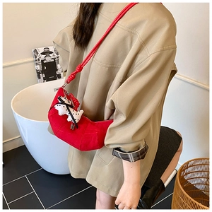 Close-up of a red croissant shoulder bag for kids with a cute dalmatian plush charm