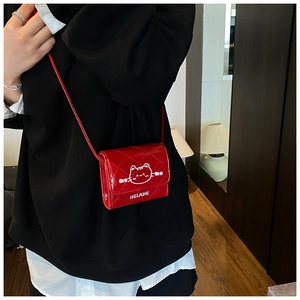 Detail of red quilted faux leather mini crossbody bag with cartoon cat and HELAHE branding