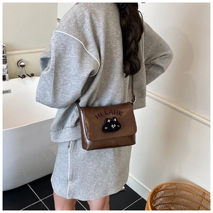 Rear view of a child wearing the brown leather crossbody bag with a cute cartoon cat