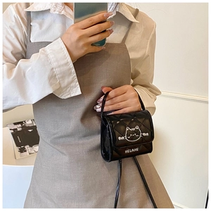 Close-up of quilted black patent leather mini bag with white cat line art and strap