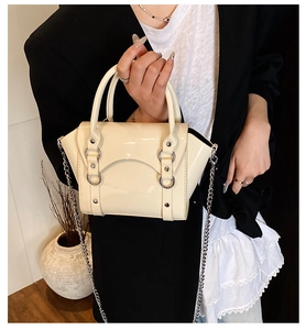 Detailed macro view of cream patent leather kids bag with silver rivet hardware