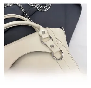 Detail show of premium silver hardware and glossy patent leather on white handbag
