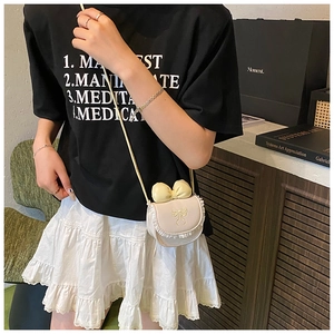 Detail of a mini cream white crossbody bag with lace trim and bow for girls