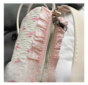Detailed close-up of the elegant silver metal zipper and pink tulle trim on the bow handbag
