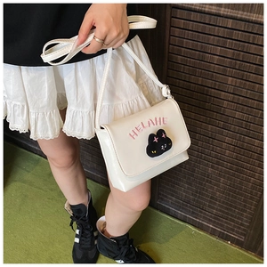 Detail of white PU leather crossbody bag with pink lettering and cute cat patch
