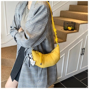 Detail of yellow matte crescent bag with cute dog pendant on model in grey plaid suit