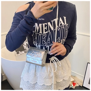 Detailed view of mini silver quilted crossbody bag with cat silhouette on model