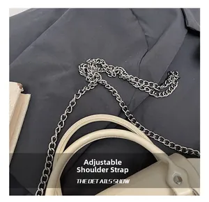 Detail of adjustable silver chain strap and smooth faux leather handle on beige mini bag