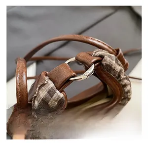 Detail shot of silver circular hardware joining brown matte leather and houndstooth fabric