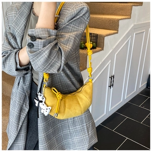 Detail of yellow crescent crossbody bag with decorative knots and puppy charm accessory