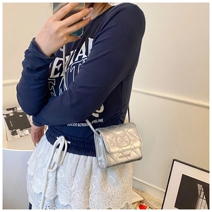 Close-up of metallic silver quilted mini crossbody bag with cute cat and chain strap