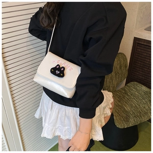 Detail showing white cartoon cat embroidery and HELLHE letters on the crossbody bag