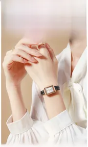 Elegante Frau mit einer quadratischen Quarzuhr aus Roségold und schwarzem Lederarmband