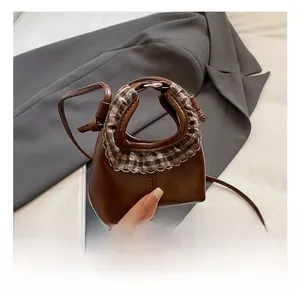 Close-up of mini brown leather kids handbag featuring checkered ruffle trim and slim strap