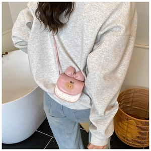 Détail du sac à bandoulière rose pomme avec nœud et motif à pois blancs pour enfants