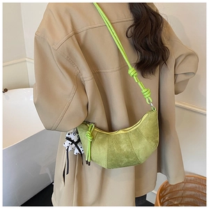 Close-up of avocado green suede half-moon bag with patchwork design and knotted strap