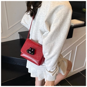Close-up of red leather kids crossbody bag with 3D cat mascot and embossed lettering