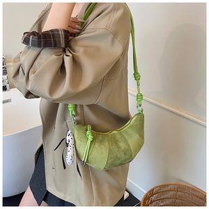 Detail of light green matte crescent bag with knot strap and dalmatian pendant