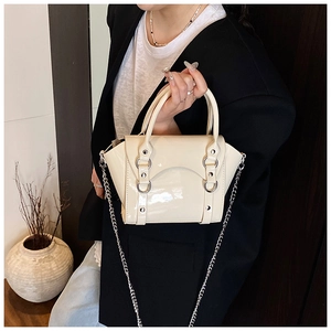 Close-up of a cream patent leather mini handbag with silver hardware and chain strap details