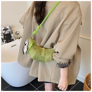 Detail of lime green matte crescent bag with chunky knot strap and polka dot bow charm