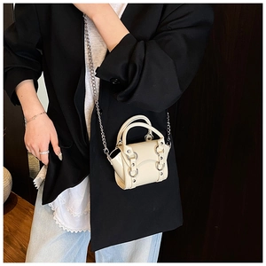 Detail of cream patent leather mini bag with silver metal ring and chain strap