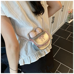 Close-up of mini silver toddler crossbody bag with pink bow and lace worn by girl