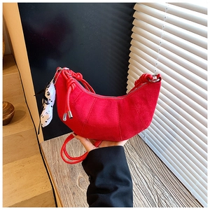 Detail of red matte suede croissant bag for kids featuring a cute dog charm accessory