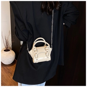 Detail of mini cream patent leather handbag with silver chain and metal rivet accents