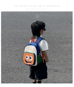 Detailed view of kids cartoon backpack featuring colorful contrast patchwork and smiley face