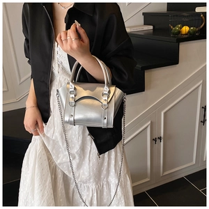 Detail view of silver metallic mini bag with rivets and chain strap in home setting