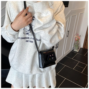 Detail of a black shiny leather crossbody bag with cute cat patch on a child model