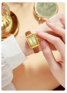 Detail einer eleganten Damen-Viereckuhr mit Goldgehäuse und braunem Lederarmband am Handgelenk