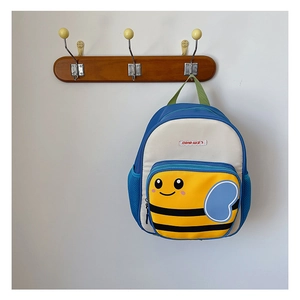 Detailed view of kids cartoon bee backpack hanging on a wooden hook against white wall