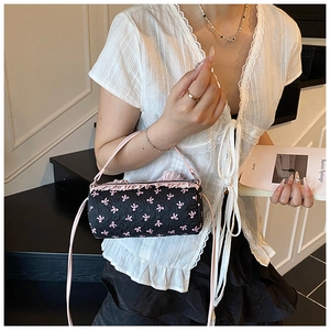 Cylindrical pink bow bag with ruffle trim and shoulder strap shown in lifestyle scene