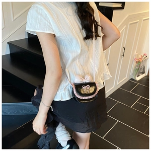 Detail of sweet pink bow and ruffle trim on black mini crossbody bag for girls