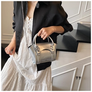 Detail view of silver mirror patent leather mini bag with chain strap on a model