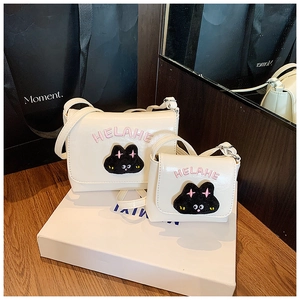 Detail view of white PU leather crossbody bags with cute rabbit embroidery and letter text