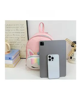 Size comparison of unicorn backpack with tablet and phone on minimalist background