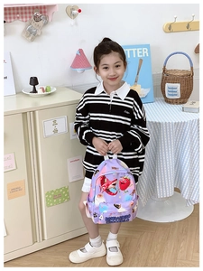 Detail of purple cartoon kids backpack with shark and strawberry prints for school