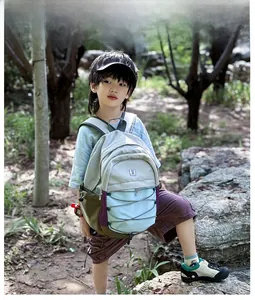 Toddler model wearing a multi-color lightweight backpack in an outdoor forest setting
