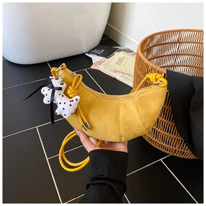 Detail of yellow crescent croissant bag in matte finish with a cute puppy charm