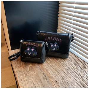Detail of black PU leather kids crossbody bags with cute plush cat patches and embroidery