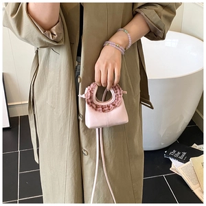 Pink mini crossbody bag featuring ruffled plaid handles and a sleek faux leather finish