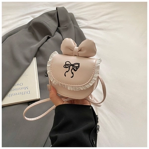 Detail of pink toddler crossbody bag with lace trim and bow embroidery held by hand