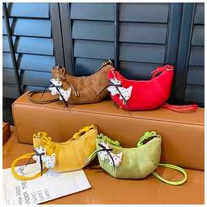 Detail of colorful matte crescent shoulder bags with knot straps and puppy pendants