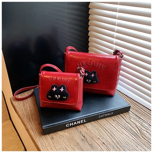Detail showing two red leather kitty crossbody bags with plush cat and letter accents