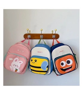 Various cute cartoon toddler backpacks including pink rabbit and striped bee on wooden hooks