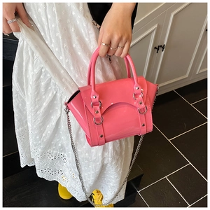 Detail of glossy bright pink patent leather handbag with silver chain and metal buckle
