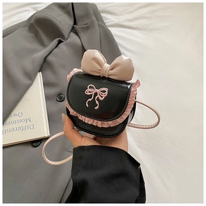 Detail of mini black crossbody bag with pink bow, ruffled lace edges and embroidery