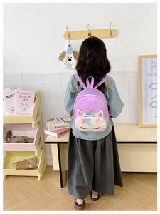 Detail of cute purple unicorn toddler backpack with rainbow front pocket shown in kids room